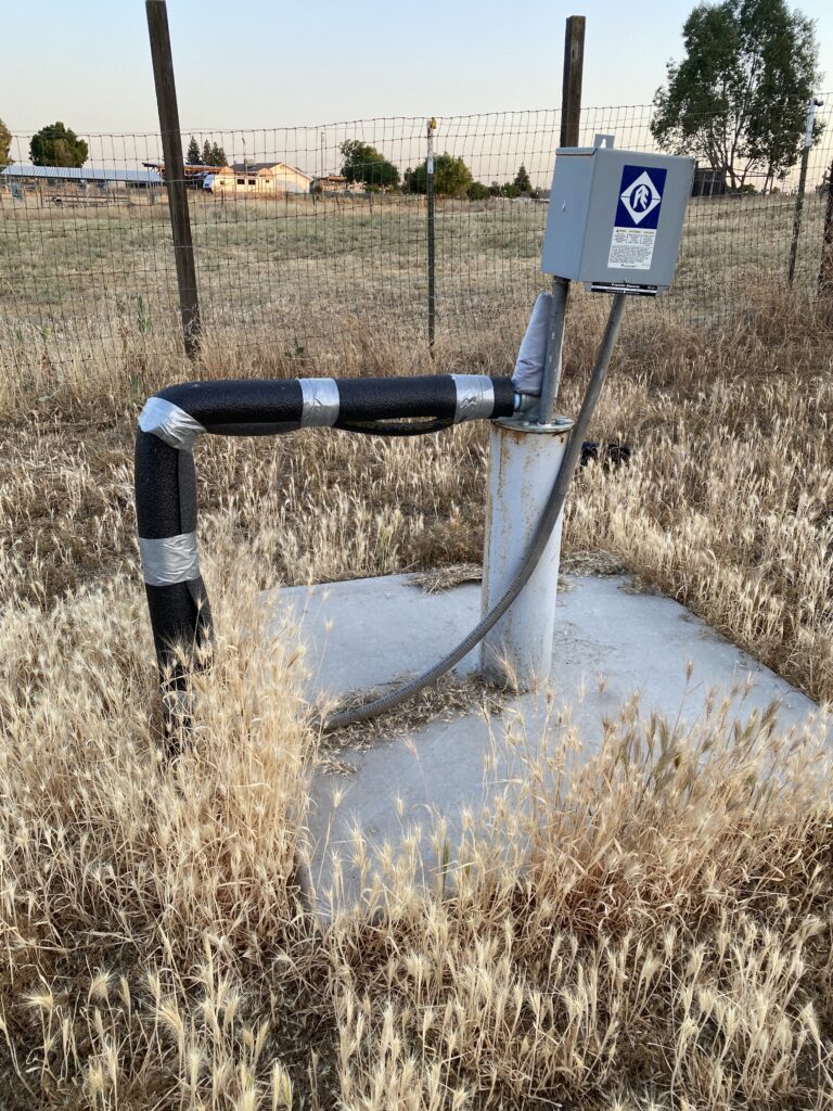 A well head with control box, pipe and heavy wires